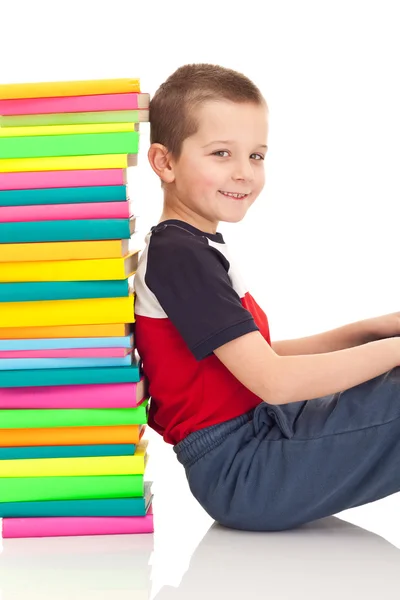 Boy sitting next to stack of books — Stock Photo, Image