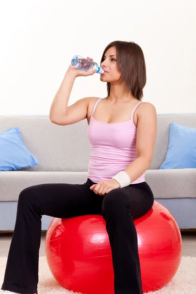 Женщина с бутылкой воды и гимнастическим мячом — стоковое фото