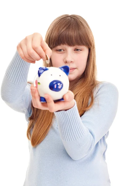 Девочка-подросток кладет монетку в копилку — стоковое фото