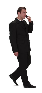 Image of a young businessman walking and using his mobile phone,isolated against a white background. clipart