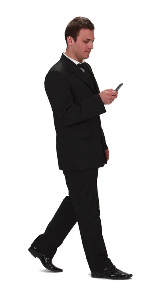 一个年轻的商人走和检查他的手机 白色背景上孤立的形象 — 图库照片