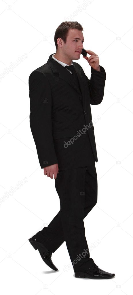 Image of a young businessman walking and using his mobile phone,isolated against a white background.