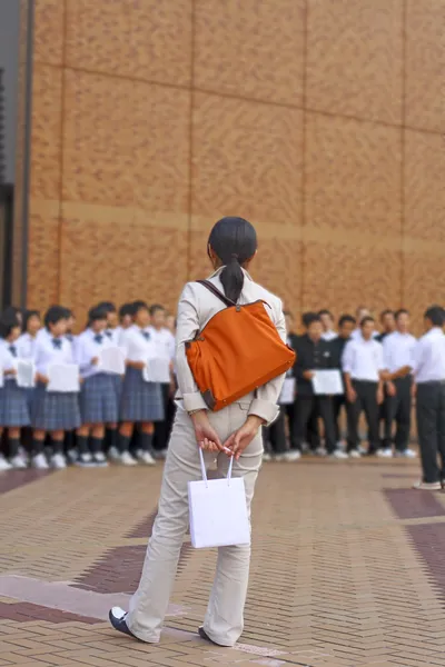 都市における子供のコーラス番組を探して袋を持つ女性 — ストック写真
