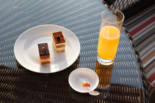 Стакан апельсинового сока и закуски на ротанговом столе — стоковое фото