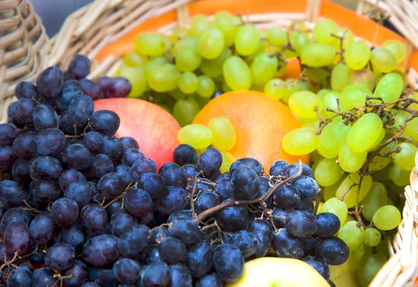 Green and black grapes in a wattled basket — Stockfoto