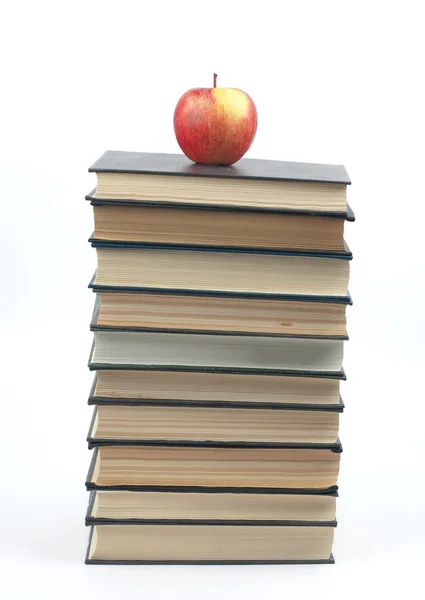 Яблоко лежит на груде книг — стоковое фото