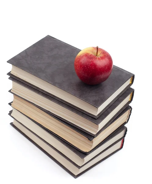 Яблоко лежит на груде книг — стоковое фото