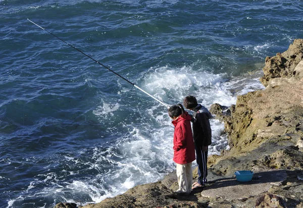 Два молодых рыбака на скалах — стоковое фото