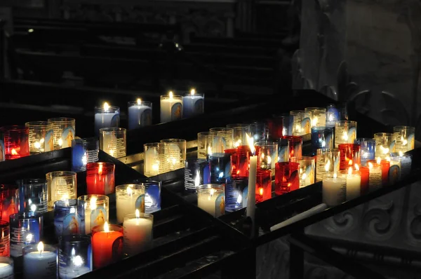 stock image Lot of religious candles on a black support in a church