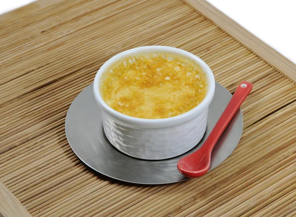 stock image Custard with an iron steel saucer and a red ceramic spoon on a bamboo tray