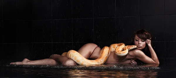 Schöne Frau liegt mit Python im Wasser — Stockfoto
