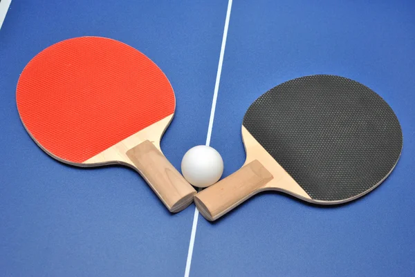 乒乓球球拍和球在乒乓球桌上 免版税图库照片