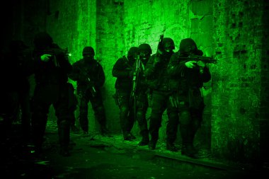 Subdivision anti-terrorist police during a black tactical exercises. Entry to the premises. Real situation. View through the night vision device. clipart