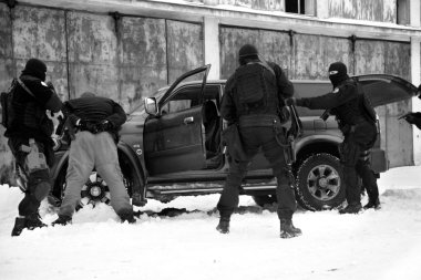Subdivision anti-terrorist police during a black tactical exercises. Stopping the suspected vehicle and drivers. Real situation. Photo with film grain. clipart