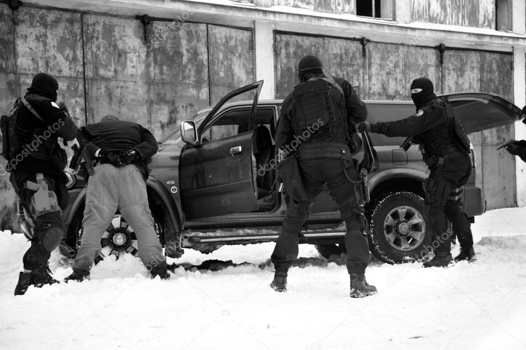 Subdivision anti-terrorist police during a black tactical exercises. Stopping the suspected vehicle and drivers. Real situation. Photo with film grain.