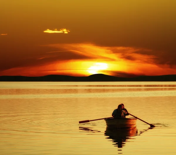 Casal remo barco ao pôr do sol — Fotografia de Stock
