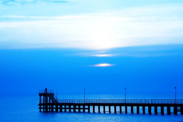 Koppel op een pier bij zonsondergang — Stockfoto