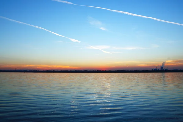 湖の工場があり、地平線上に沈む夕日 — ストック写真