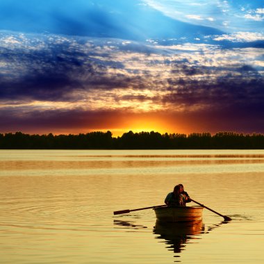 Couple in boat against a beautiful sunset clipart