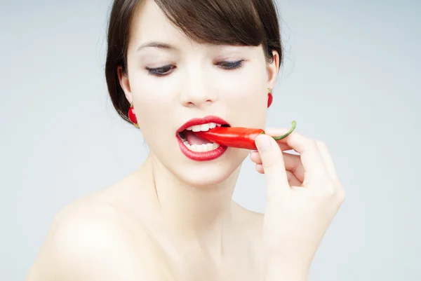 Sexig kvinna biter en chili peppar — Stockfoto