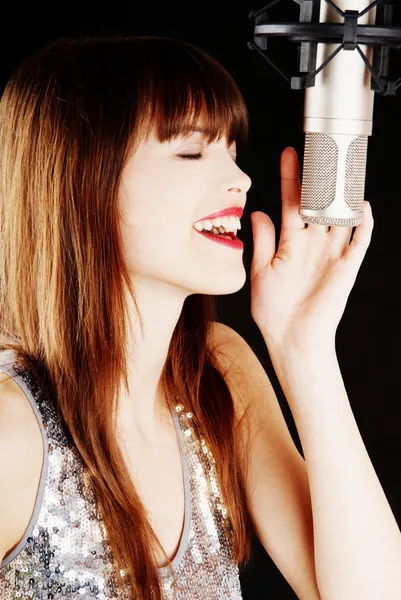 Девушка поет под микрофон в студии — стоковое фото