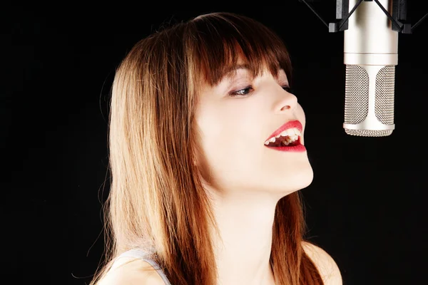 スタジオでマイクに歌っている女の子 — ストック写真