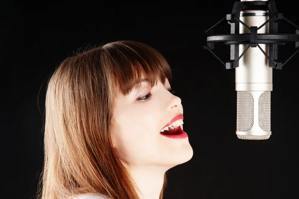 Menina cantando para o microfone em um estúdio — Fotografia de Stock