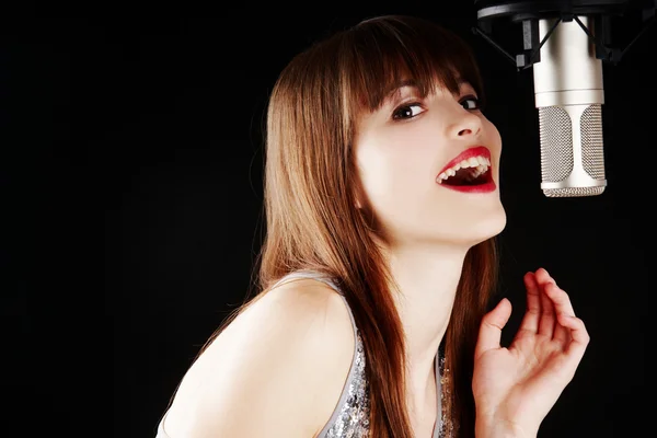 Девушка поет под микрофон в студии — стоковое фото