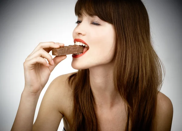 Mujer sexy comiendo una barra de chocolate - filmado en estudio —  Fotos de Stock
