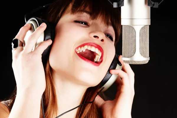 Girl singing to the microphone in a studio — Stock Photo, Image