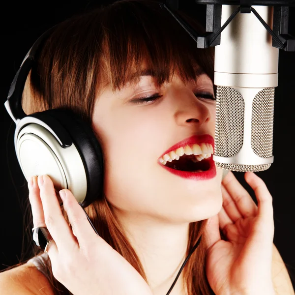 Mädchen singt im Studio ans Mikrofon — Stockfoto