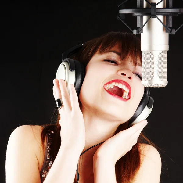Ragazza che canta al microfono in uno studio Foto Stock Royalty Free