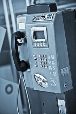 Close up view of public phone on blue back clipart