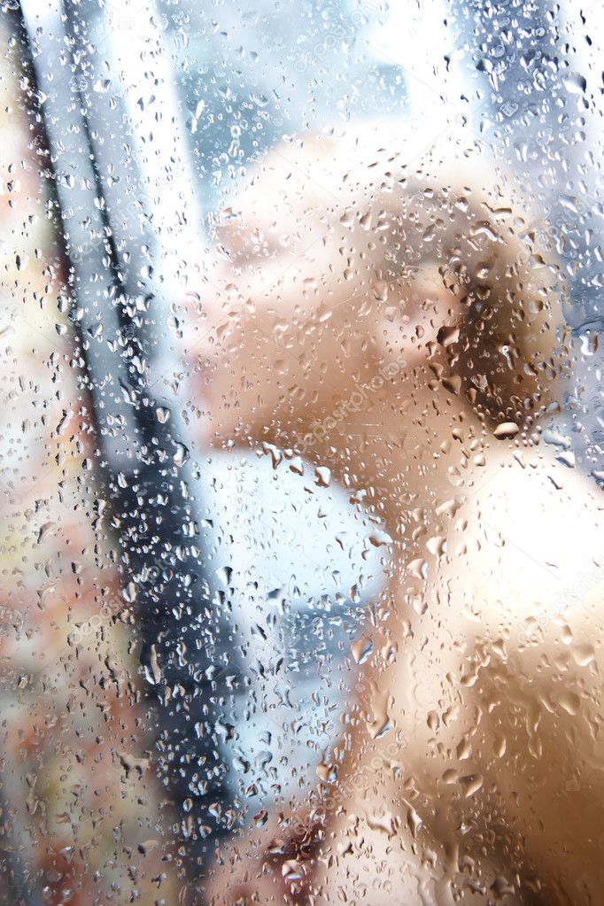 Shower drops blurred close up photo of young woman taking shower. Focused o