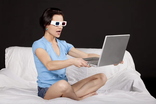 Pretty young woman sitting on bed with her laptop — Stock Photo, Image