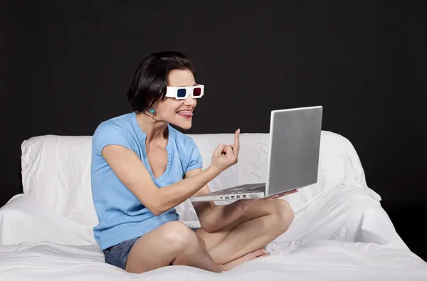 Красивая молодая женщина сидит на кровати со своим ноутбуком — стоковое фото