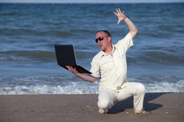 沮丧的晒伤的商人在沙滩上与他的笔记本电脑 — 图库照片