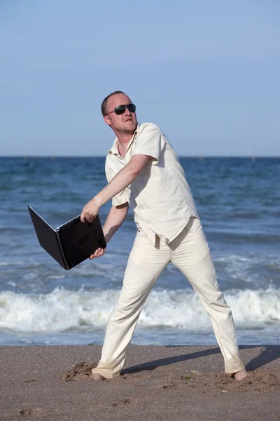 Rozhněvaný muž hodil svůj notebook na pláži — Stock fotografie