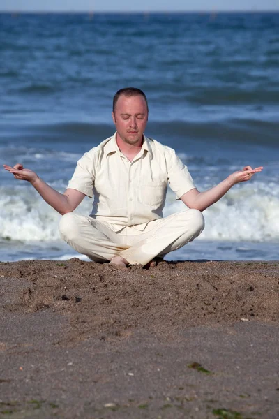 Jonge zakenman doet yoga op een strand — Stockfoto