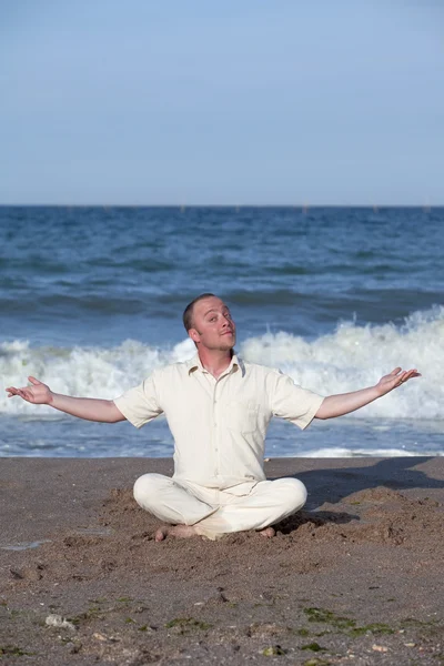 Joven empresario haciendo yoga en una playa —  Fotos de Stock