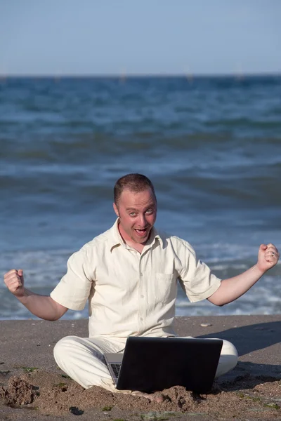 年轻的商人 在沙滩上与他开心关于成功的笔记本电脑 — 图库照片