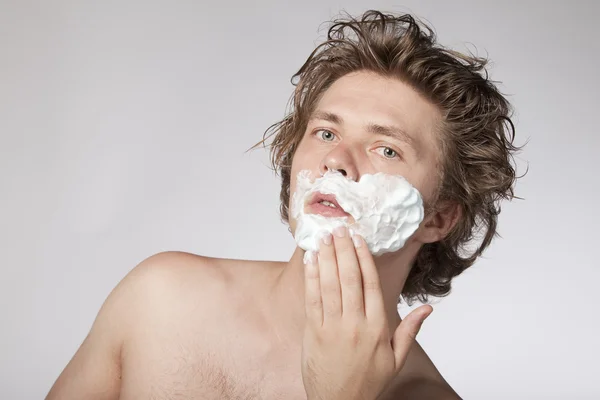 Привлекательный молодой человек бреется — стоковое фото