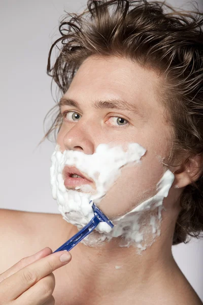 Привлекательный молодой человек бреется — стоковое фото
