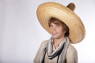 Happy young mexican man with sombrero looking at the camera and smiling clipart