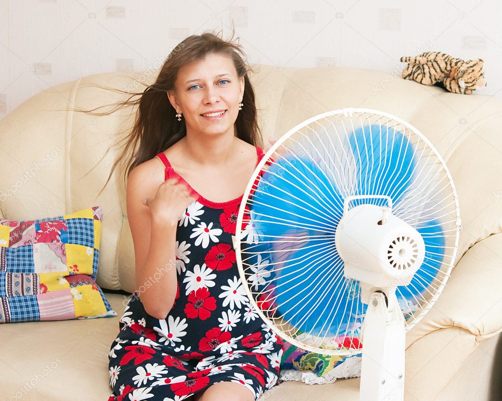 The girl sits in front of the fan