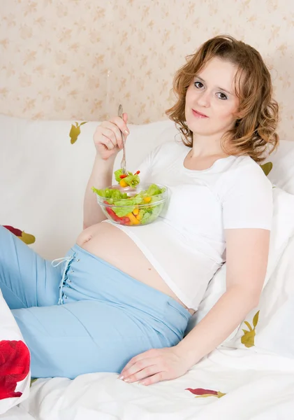 Mujer embarazada en la cama comiendo —  Fotos de Stock