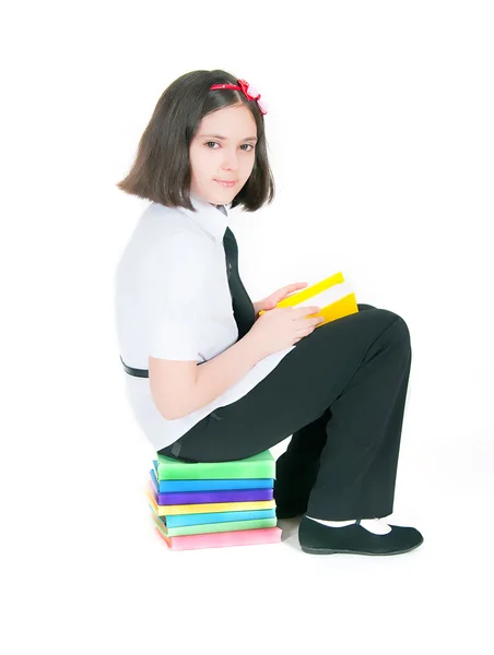 Meisje, zittend op een stapel boeken — Stockfoto