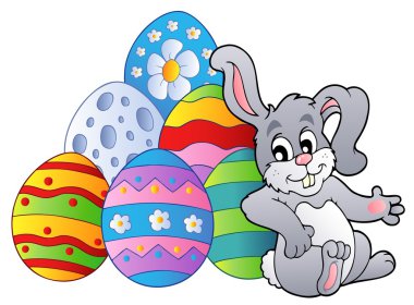 Bunny resting beside Easter eggs clipart