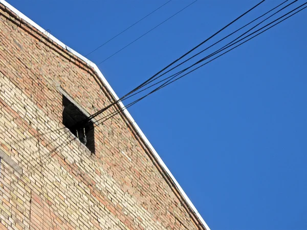 Mur en brique rouge, câbles du grenier, connexions sur ciel bleu . — Photo