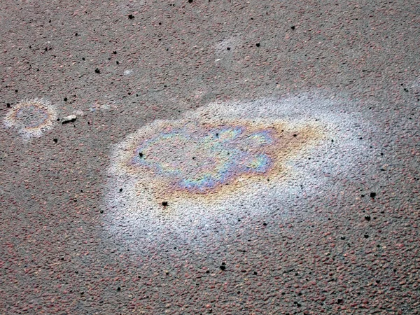 Färg bensin bränsle fläck på asfalt, ekologiska frågor. — Stockfoto